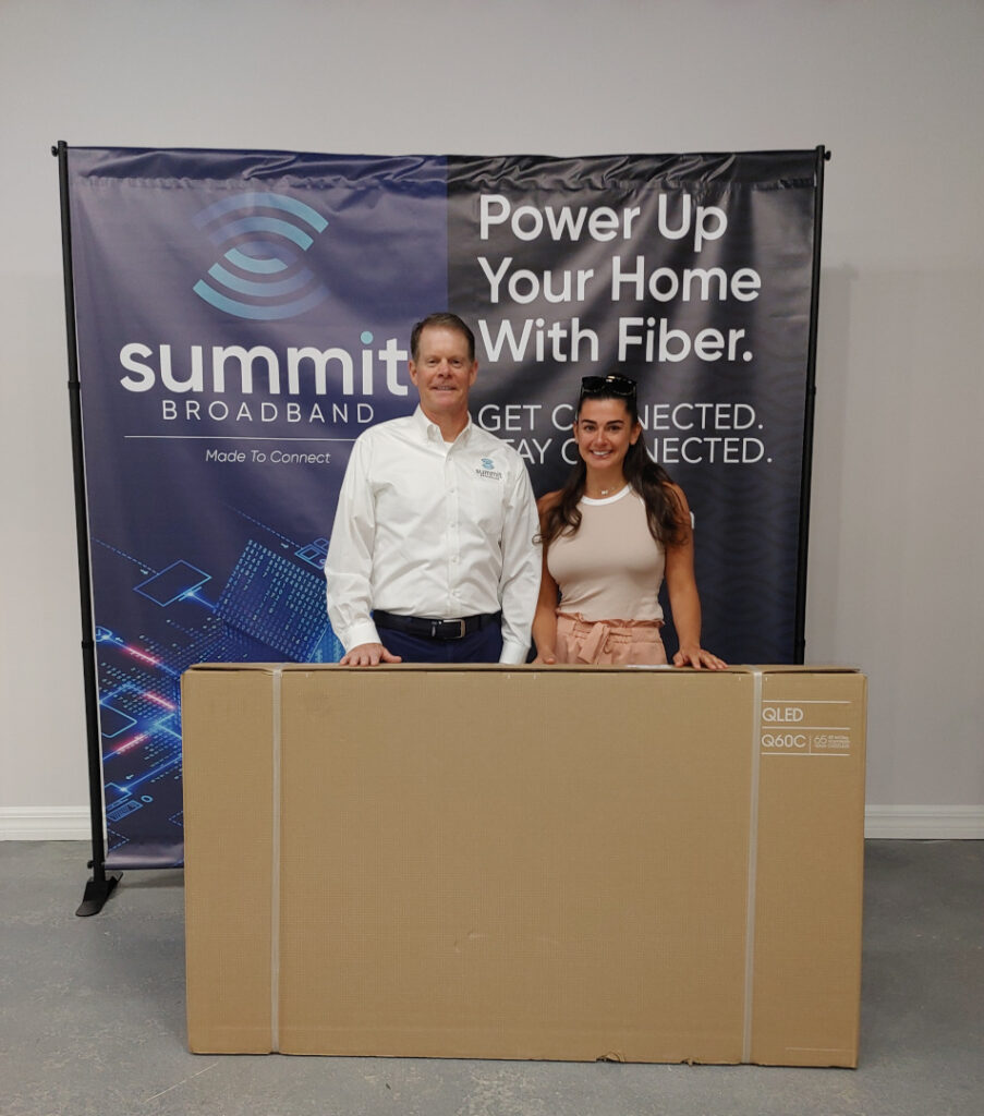 Summit Broadband holiday contest winner with her prize (65 inch Smart TV).